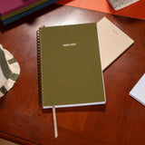 Green planner for 2026-2027 on a wooden surface with other items.
