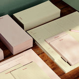 Set of stationery items including notebooks and a pen on a wooden surface.