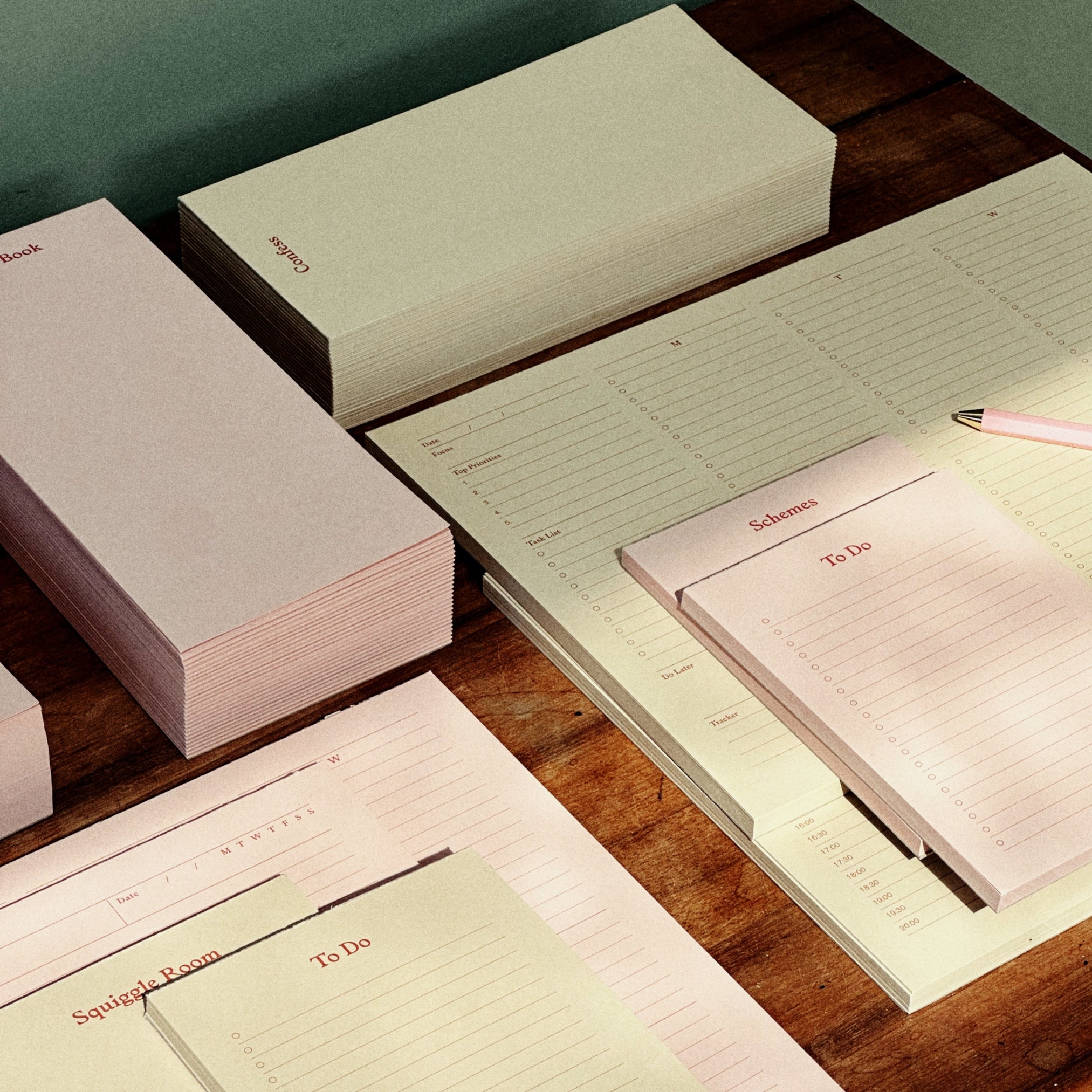 Set of stationery items including notebooks and a pen on a wooden surface.