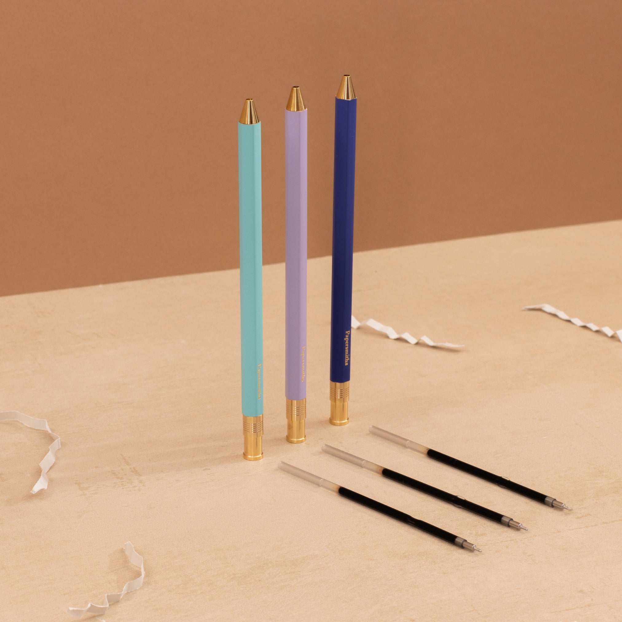 A set of three color-coded pens with gold accents and matching refills, presented on a neutral background.