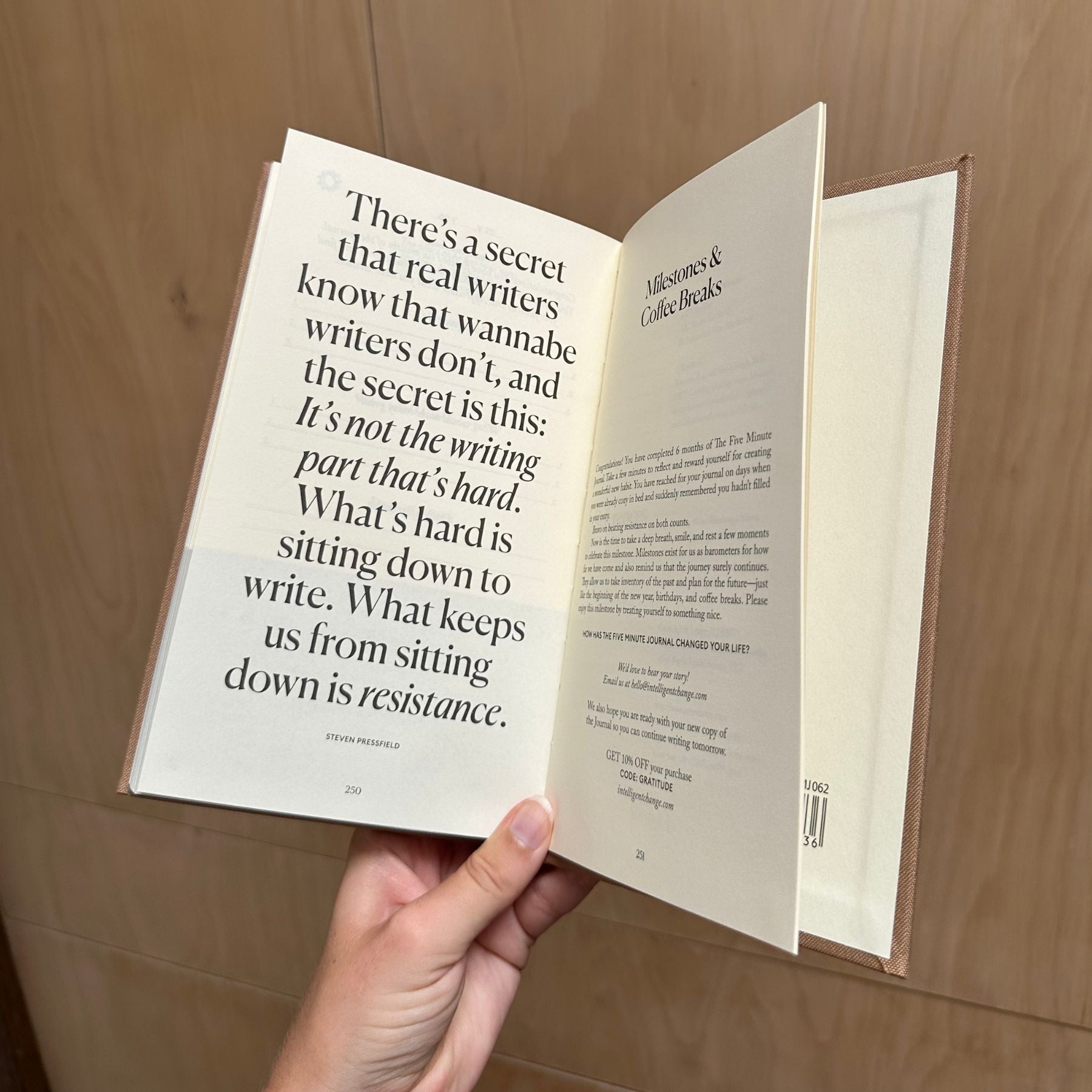 Open book with text held by a hand against a wooden background