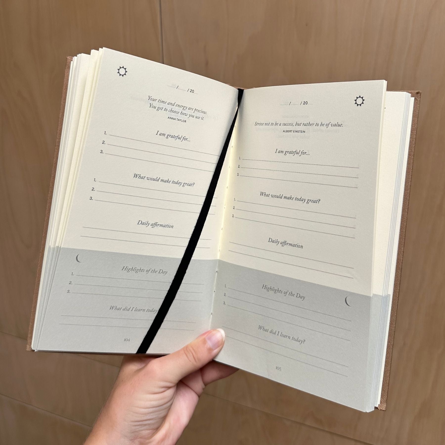 Open book with daily reflection pages held by a hand on a wooden surface
