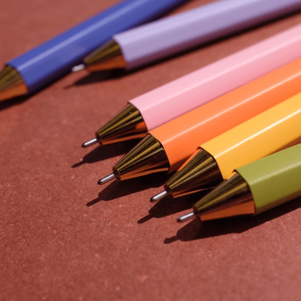 Colorful pens with gold accents on a brown surface