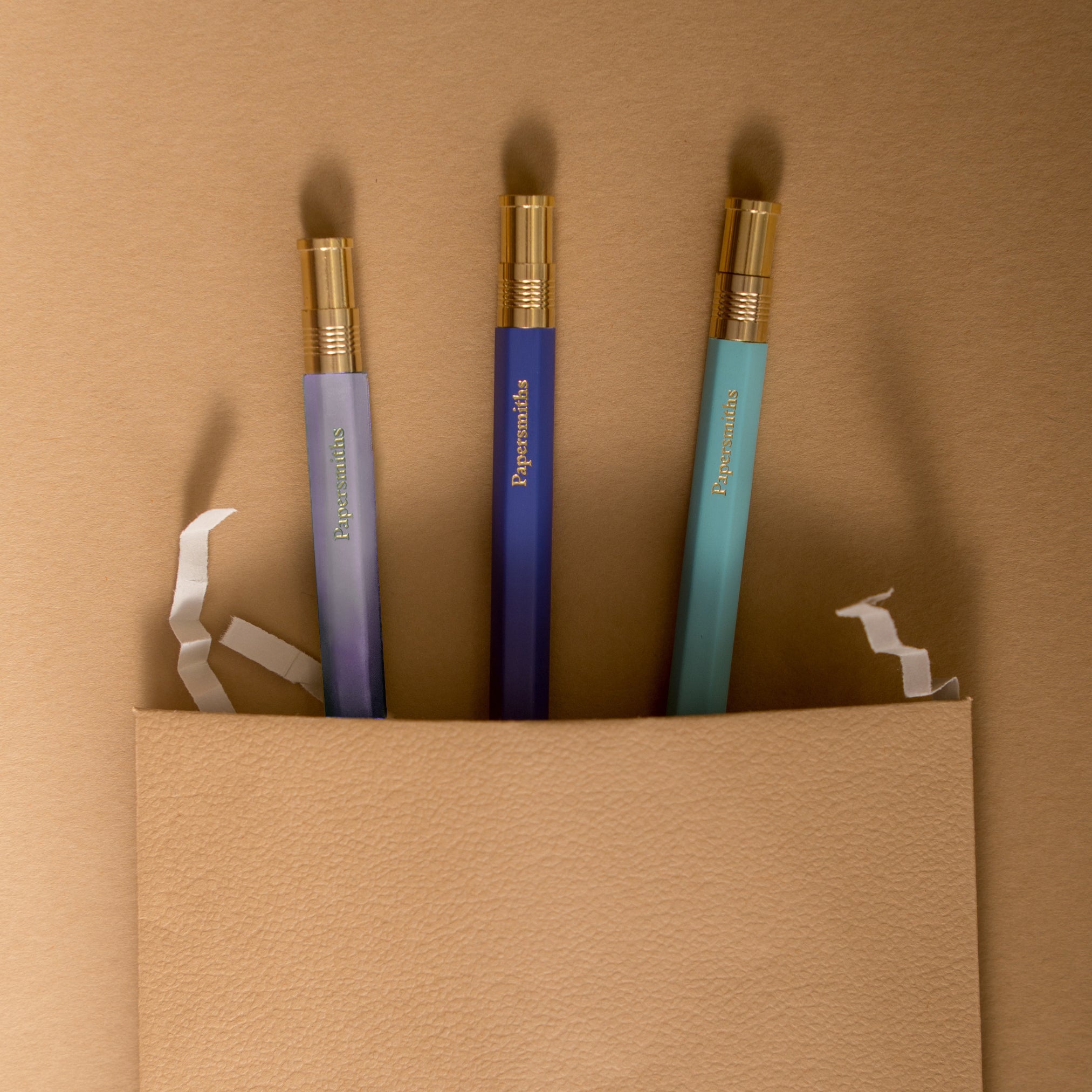 Three color-coded pens with gold accents and matching refills, presented on a neutral background.