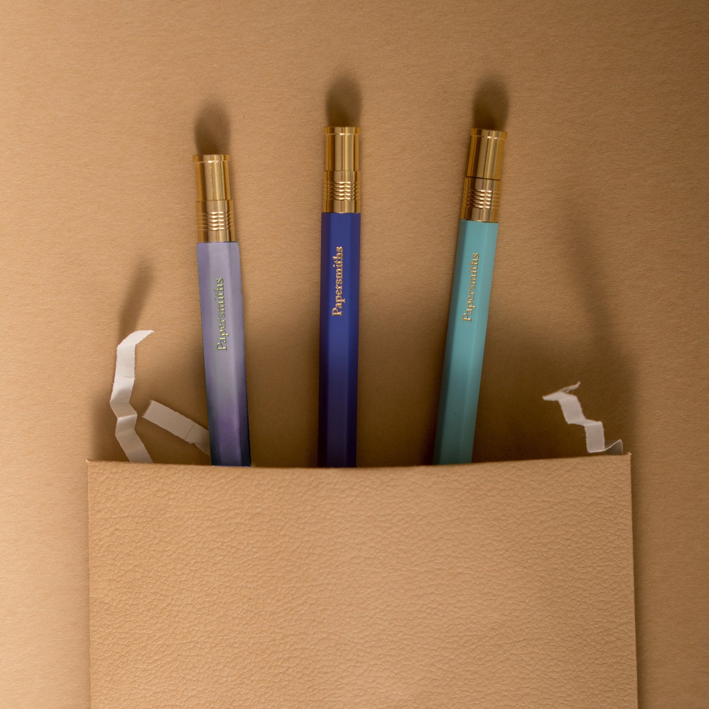 Three color-coded pens with gold accents and matching refills, presented on a neutral background.