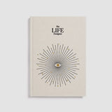 Beige book titled 'The LIFE Designer' with a starburst design on a light gray background
