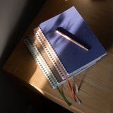 Stack of notebooks with pens on a wooden surface