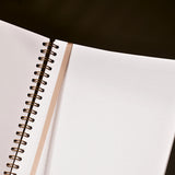 Open notebook with spiral binding on a dark surface