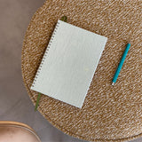 Spiral-bound notebook with a blue pen on a textured surface