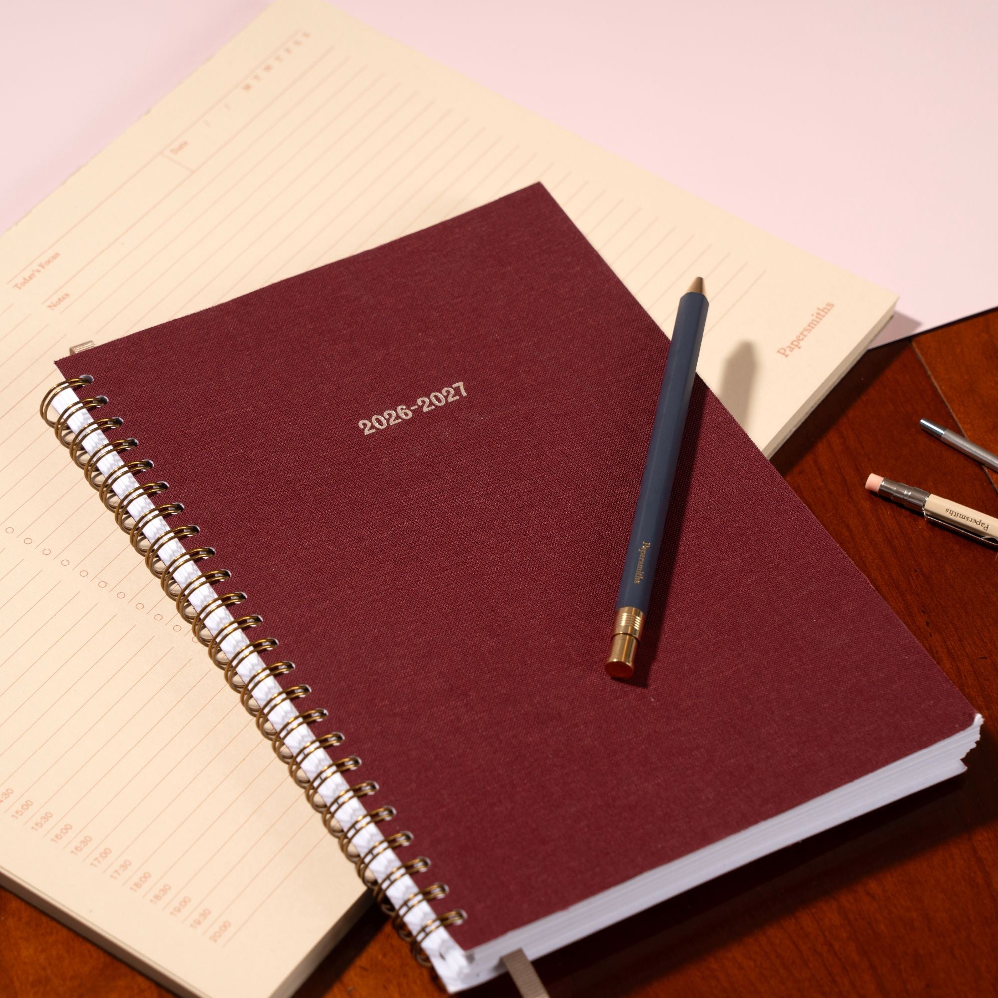 Maroon planner with a pen on a wooden surface