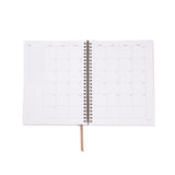 Open spiral-bound planner with grid layout on white background