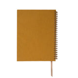 Mustard yellow notebook with a spiral binding on a white background