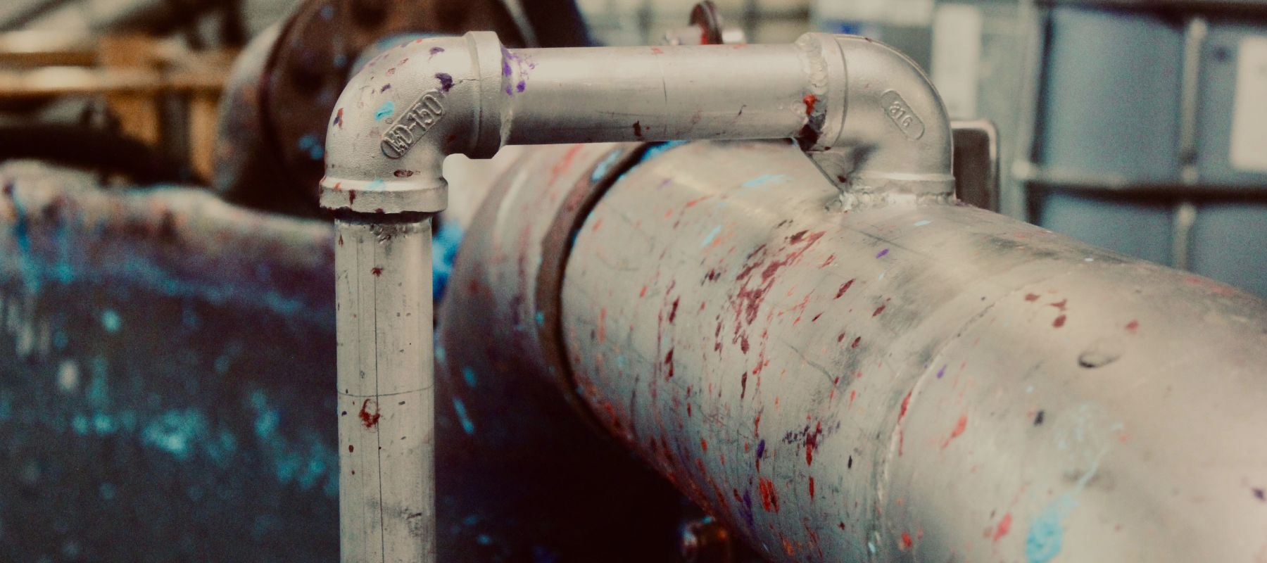 Industrial pipe with colorful paint splashes in a book binding workshop setting