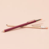 Two pocket-sized pencils with pink and beige accents on a beige background