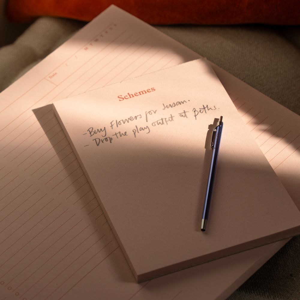 Blue pocket pen lying on a 'Schemes' note block