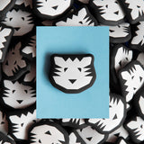 Black and white tiger head eraser on a blue card with more tiger head designs in the background.