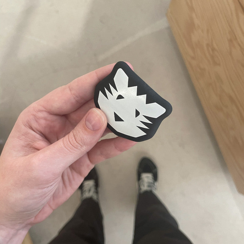 Hand holding a black and white design eraser on a neutral background